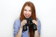 © sergeyzapotylok - Portrait of cute redhead girl wearing blue striped shirt smiling with happiness and joy while posing with binoculars against white studio background