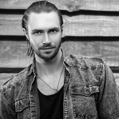 Wall Mural - Black-white portrait of young handsome long hair man against wooden background.