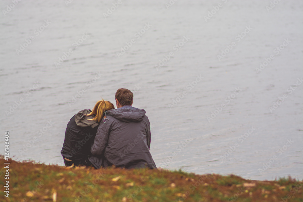 romantic couple standing on a lake shore watching sunset in beautiful ...
