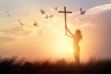 Canvas Print - Woman praying with cross and flying bird in nature sunset background