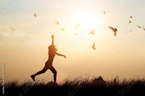 Cuadros en Lienzo Woman and flying birds enjoying life in nature on sunset background