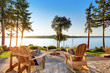 Back yard of waterfront house with adirondack chairs and fire pit