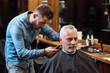 © zinkevych - Handsome barber trimming hair of old man