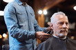 © zinkevych - Close up barber trimming hair of old man