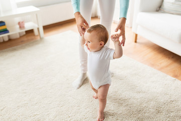 happy baby learning to walk with mother help