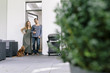 © Westend61 - Smiling couple with dog standing at terrace door