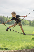 Confident Girl Walking On Rope Over Field