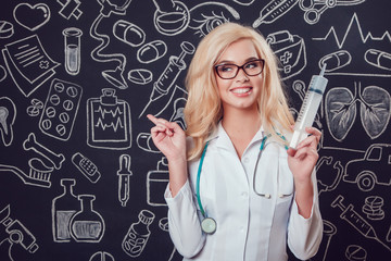 Wall Mural - Beautiful blonde woman doctor in glasses and white coat holding syringe on dark background with pattern