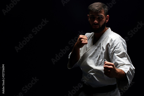 Fototapety Sztuki Walki  karate-mezczyzna-w-kimonie-w-postawie-bojowej-na-czarnym-tle