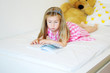 © Irina Glazaceva  - Adorable little girl lying on the bed and reading a book