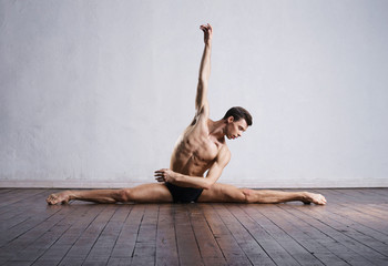 Wall Mural - Handsome ballet dancer sitting on splits