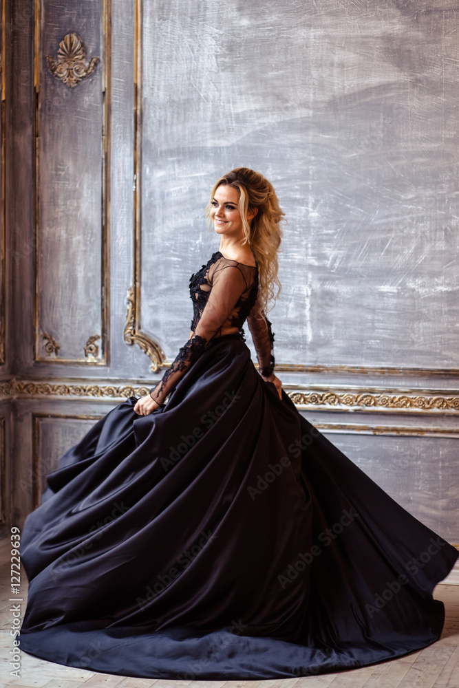 Beautiful young woman in gorgeous black evening dress with perfect makeup  and hair style Stock Photo