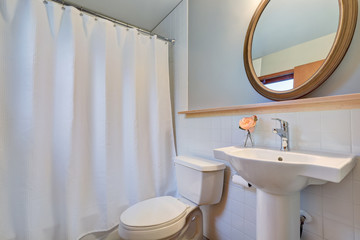 White clean bathroom with washbasin stand and a toilet.