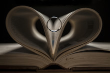 Old Book With Heart Shaped Pages. Ring Between Pages, Black Background. 