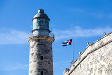 Lighthouse At Castillo Del Morro, El Morro Fort In Havana With A Waving Cuban Flag On A Clear Day