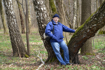 The elderly man costs having leaned against a birch in the sprin