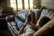 © Joshua Resnick - bearded guy relaxing on couch at home using smart phone