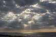 dramatic pre-sunset sky over the sea with sunbeams through clouds