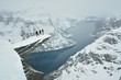 Three boys on famous Troll tongue rock during sever winter in Norway in scandinavia