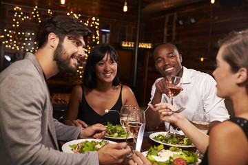 Four friends enjoying dinner and drinks at a restaurant