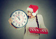 © pathdoc - stressed in a hurry woman wearing santa claus hat holding clock gift box