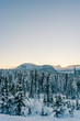 Sun setting over snowy mountain landscape evergreen trees covered in snow clear blue cloudless sky copy space