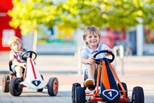 Two Active Little Kid Boys Driving Pedal Race Cars