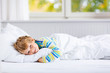 © Irina Schmidt - happy little kid boy after sleeping in bed in colorful nightwear