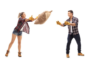 Wall Mural - Female farmer throwing burlap sack at male farmer