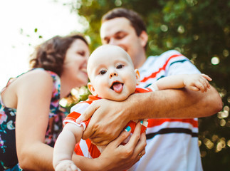 young and happy parents playing with their cute little baby outd