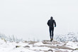 runner in black warm sportswear running in wind and fog on the high mountain trail in the winter