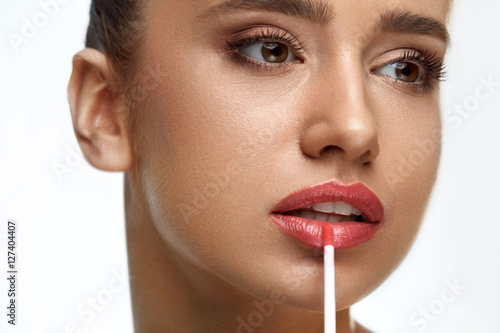 Poster Beautiful Woman Doing Makeup Using Lip Gloss On Lips. Cosmetics