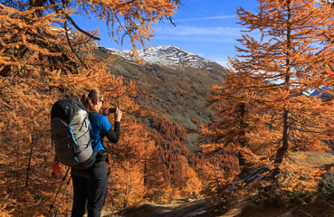 Poster - Female hiker photographing the warm autumn colors in the Claree valley, France.