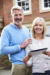 Wall Mural - Mature Couple Standing Outside House Looking At Property Details