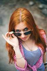 Wall Mural - beautiful young woman looking at camera through sunglasses