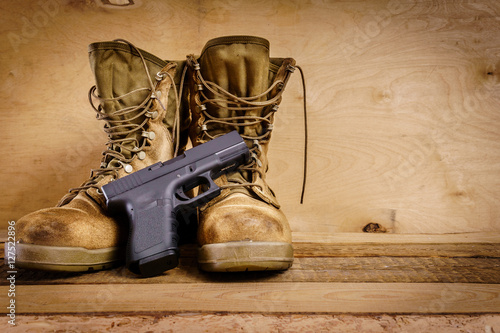 Tela used brown military boots and a gun on a wooden table