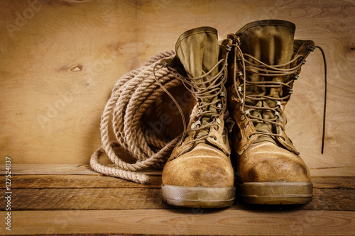 Fotografia old military boots and rope on a wooden table