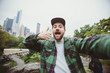 © mysh - Handsome bearded hipster taking selfie with camera in Central Park, New York. Happy student makes funny picture for his blog.