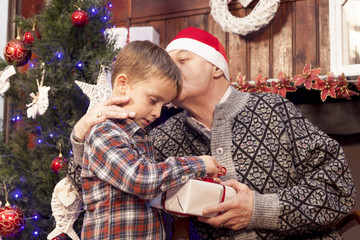 adorable little boy gives a christmas gift to his grandfather