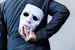 © twinsterphoto - Business man carrying white mask to his body indicating Business fraud and faking business partnership