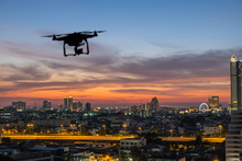 Silhouette Of Drone Flying Above The City At Sunset Time