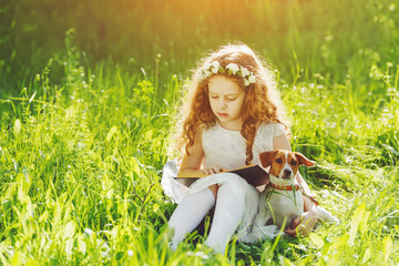 Wall Mural - Little girl reading a book with her friend puppy dog in the outd