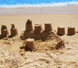 Turret tower from golden sand on the beach in the morning near the sea in the summer holiday at a resort in the sunshine. Children's Entertainment to build a tower of sand with the help of a bucket.
