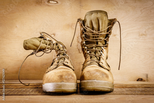 Fotomural Viejos botines marrones militares en una mesa de madera