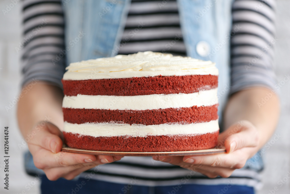 Woman holding delicious cake on blurred white brick wall background