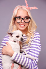 Wall Mural - Beautiful girl holding cute dog on grey background