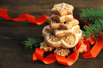 Wall Mural - Stack of tasty gingerbread cookies, ribbon and Christmas tree branch on wooden background, close up view