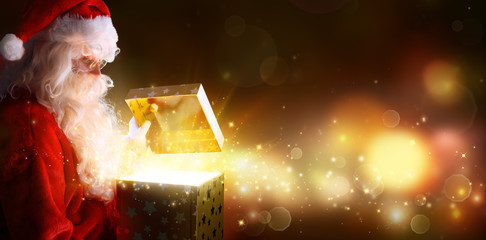 santa claus opening christmas present with shiny lights