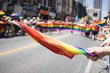 People participating in the World Pride Parade in Toronto. Spectators can be seen beside the path holding a rainbow flag. LGBTQ