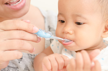 mother teaching baby girl teeth brushing